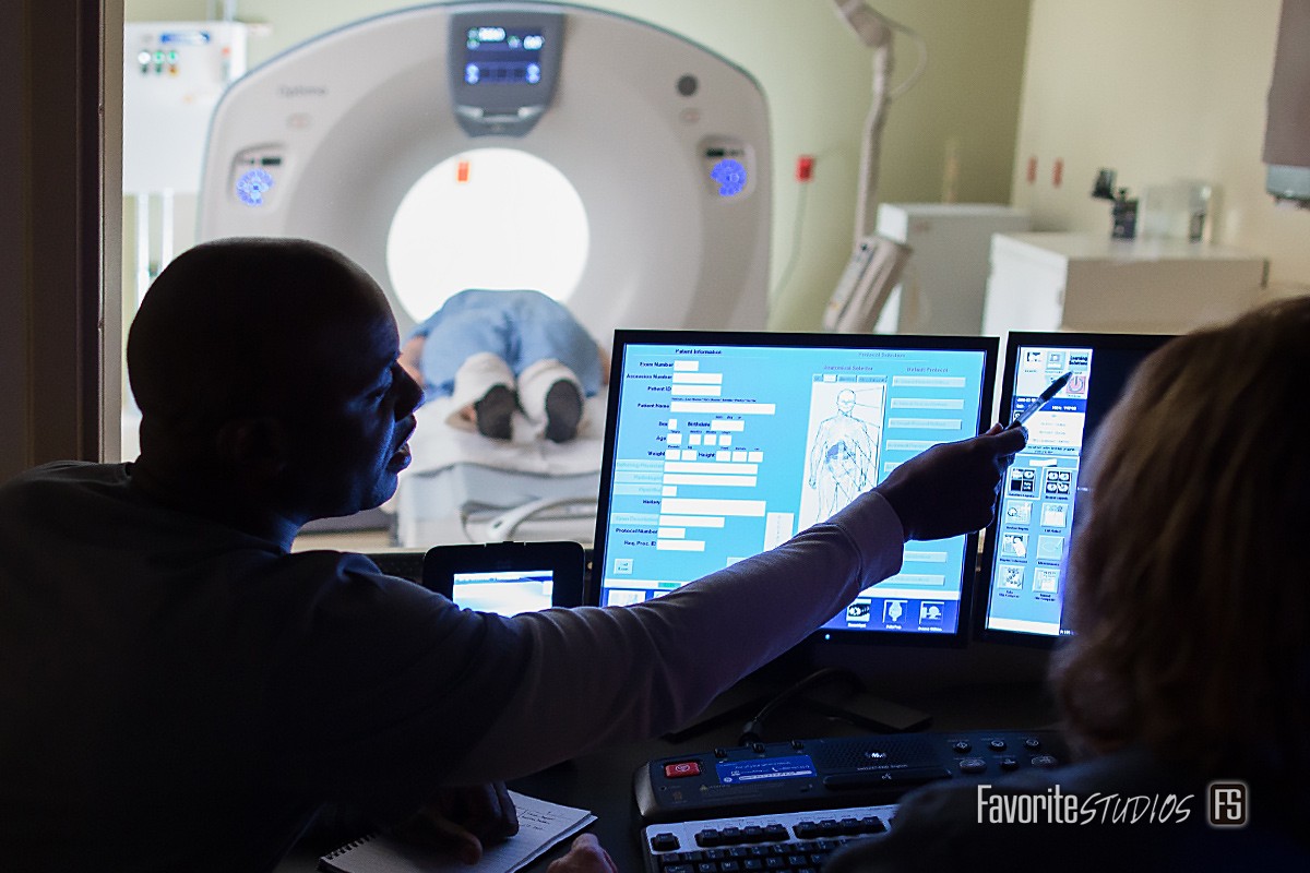 Photograph at imaging center of MRI in progress with patient and employees, following HIPPAA privacy rules. Health care photography and videography by Favorite Studios.